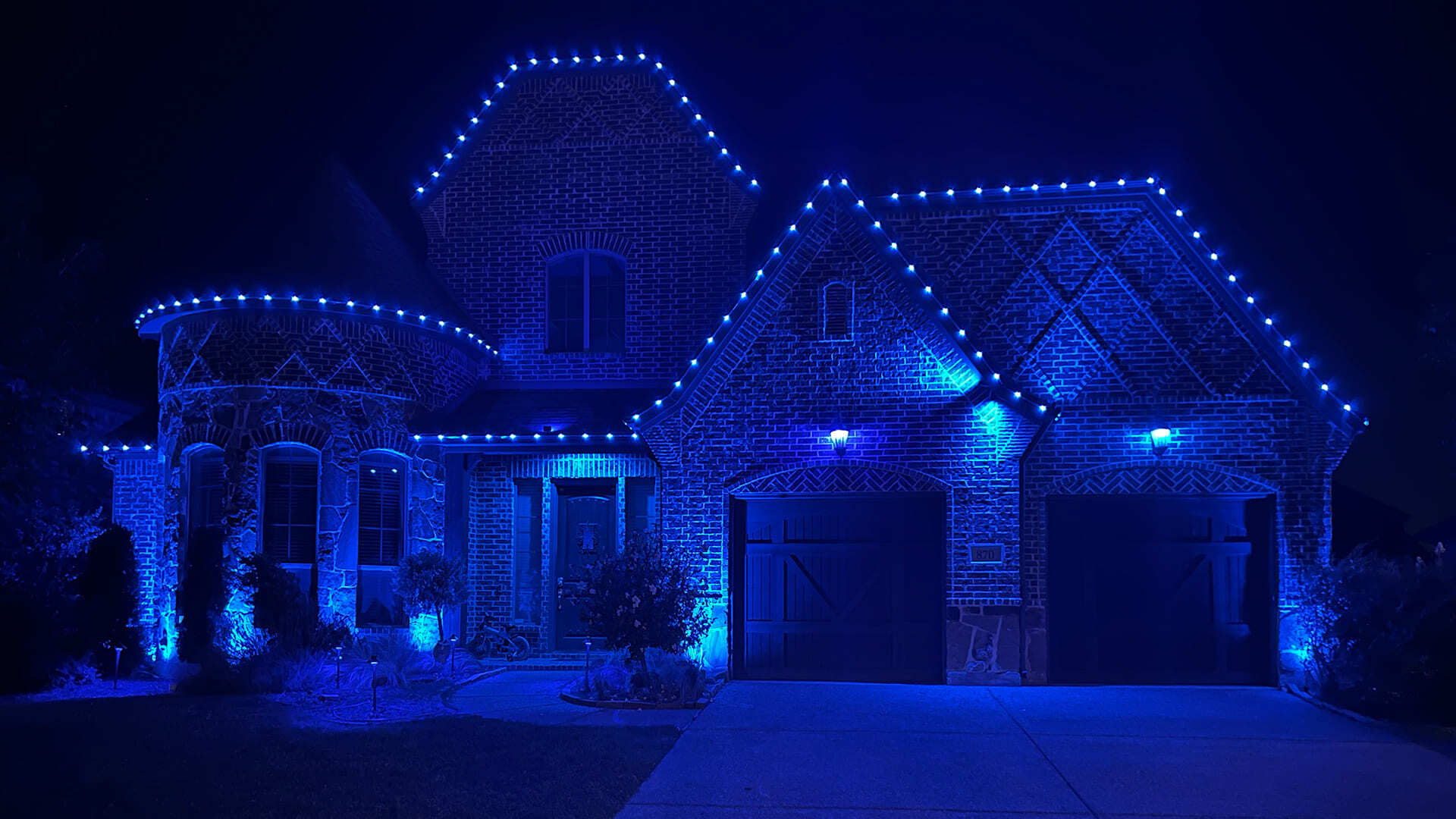 Colorado home illuminated with custom blue permanent outdoor LED lighting for a special event.