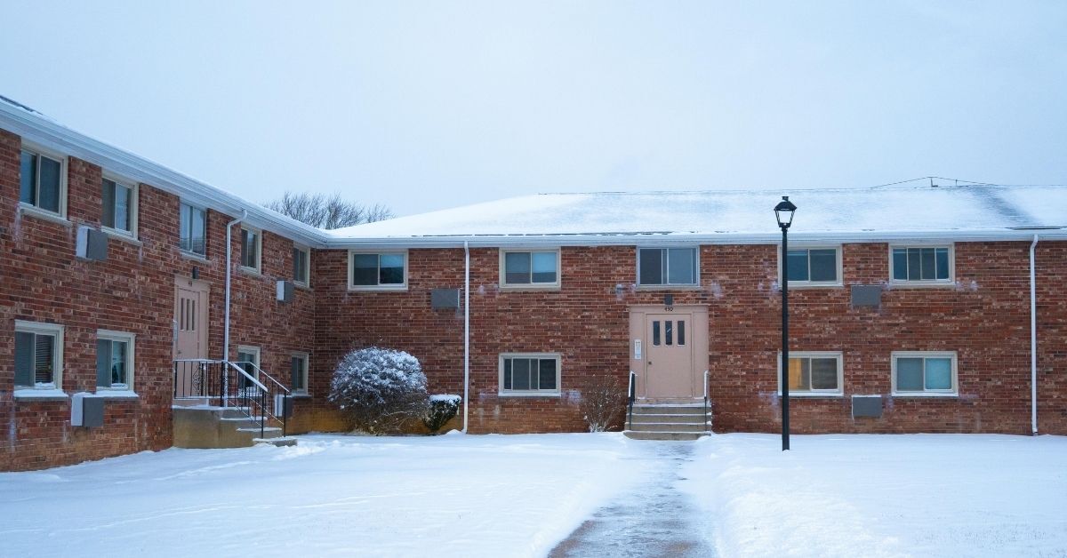 Multifamily apartment property with snow-covered grounds and cleared walkway