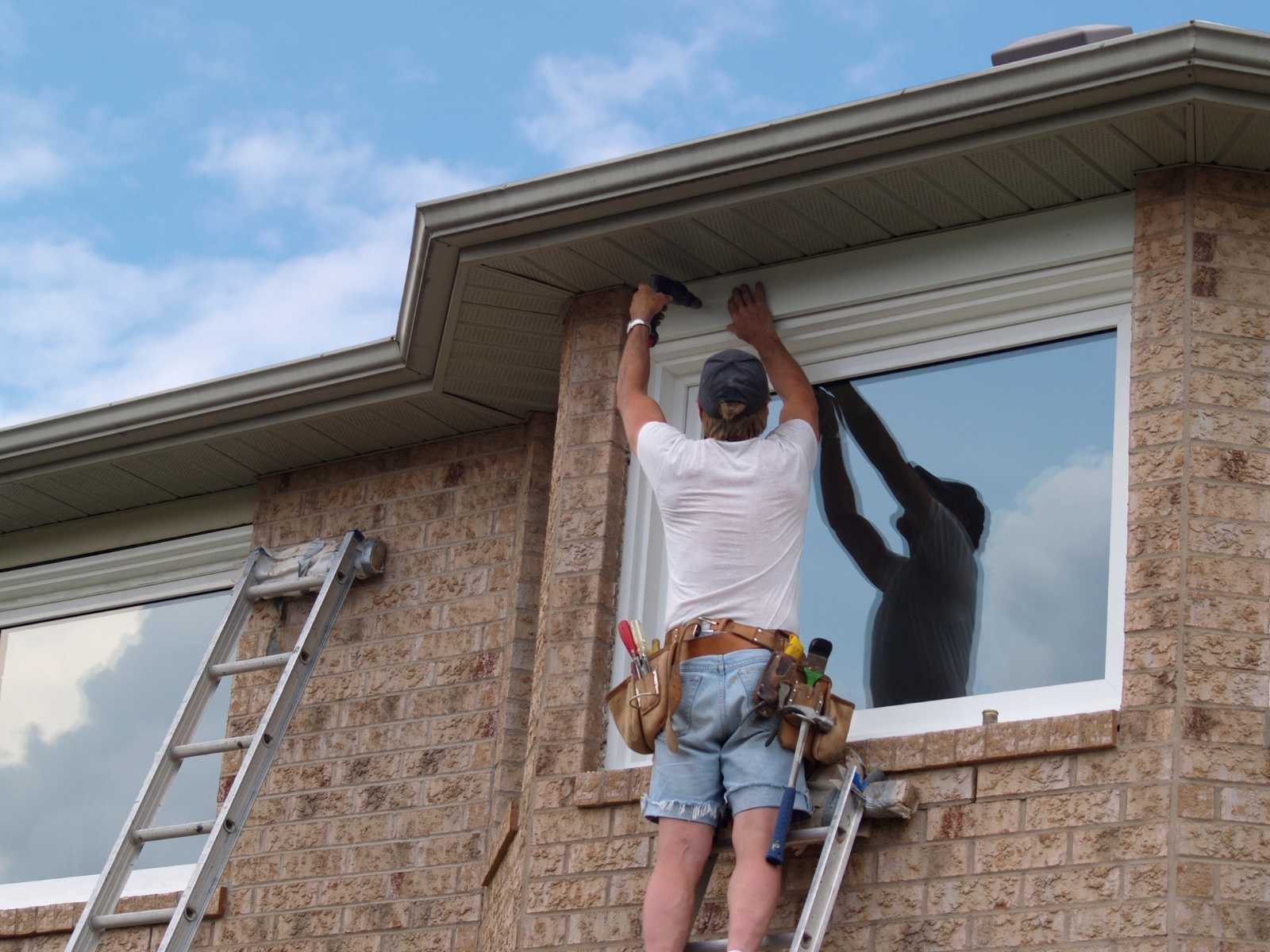 Installer completing a replacement window installation on a brick home Installer completing a replacement window installation on a brick home